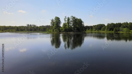 The view from the drone over the forest areas and the lake nestled among green trees.There is a small island on the lake and a small river flows through the lake