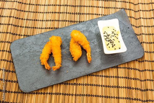 Fotografie Prawn ebi tempura with seed sauce to dip on a black slate tray on a stitched woo