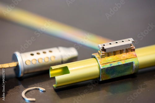 Spring compressed cylinder lock with pins exposed.  Various tools and parts shown in the background photo