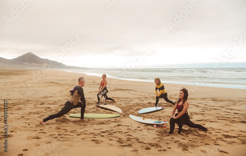 Group of people stretching at the beach, before starting a surf session