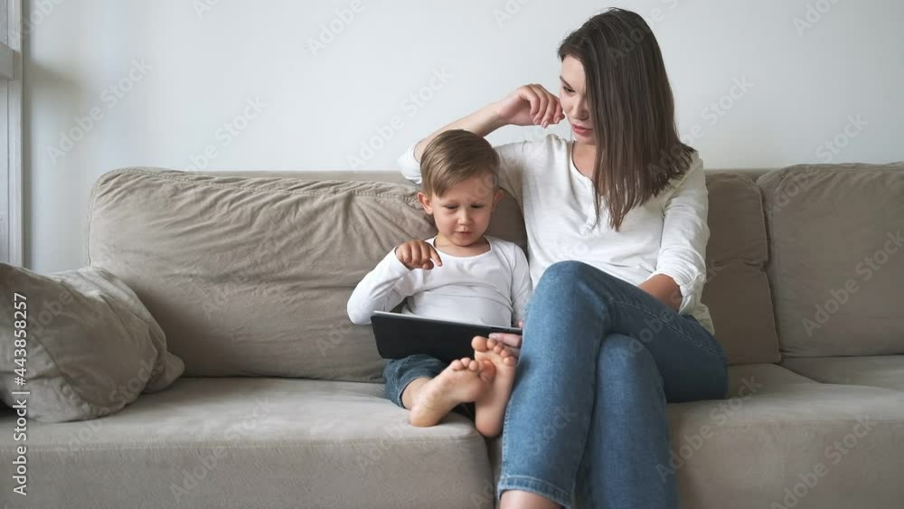 Family mother and child using tablet sitting on sofa at home Family mother and child using tablet sitting on sofa at home