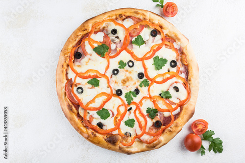 Pizza with sausage, ham and pork, mushrooms, bell pepper, tomatoes, Mozzarella cheese and olives on a light background.