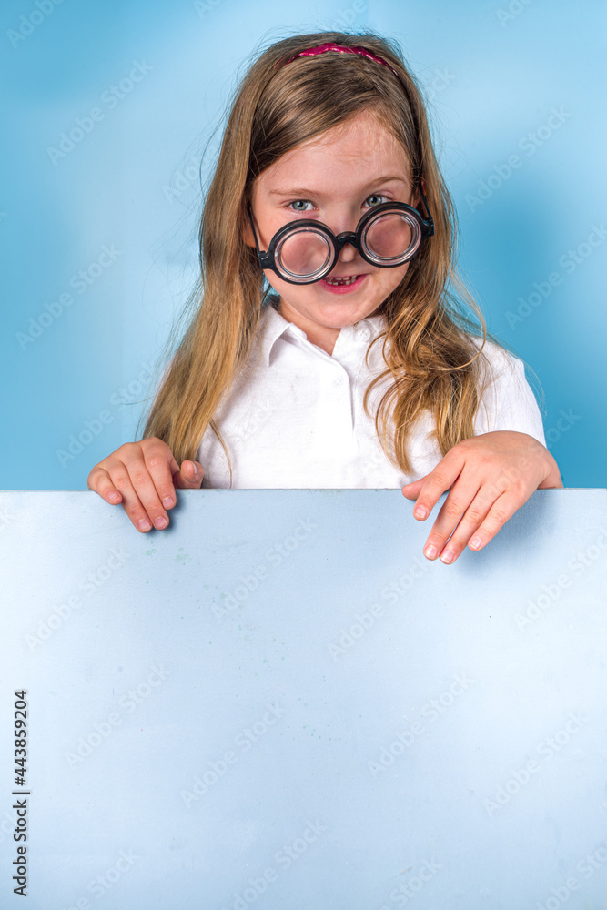 Back to school concept. School invitation, advertisement banner. Cute primary student schoolgirl in white blue classic uniform, funny glasses. Colorful bright blue trendy background copy space Back to school concept. School invitation, advertisement banner. Cute primary student schoolgirl in white blue classic uniform, funny glasses. Colorful bright blue trendy background copy space