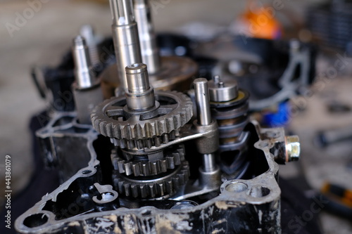 A motorcycle mechanic is working on the engine gear.