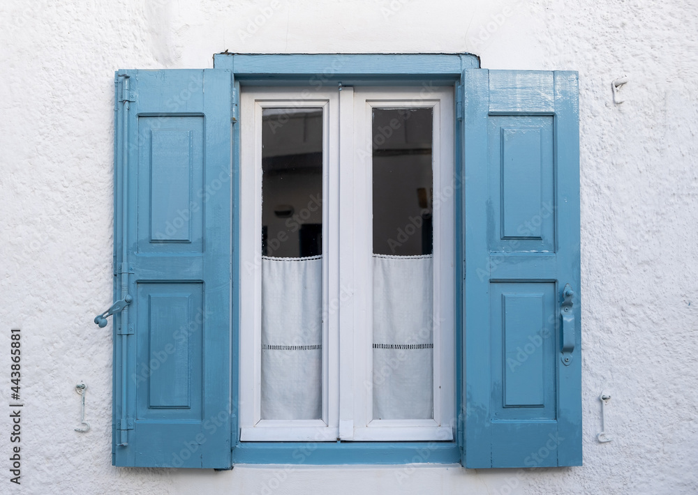 Wooden blue color window on a whitewashed wall. Greece, Cyclades.