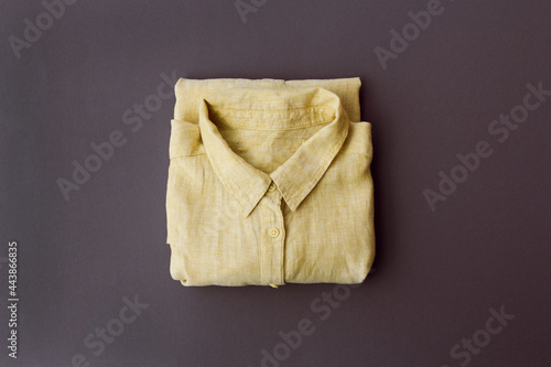 neatly folded yellow shirt on a gray background, top view