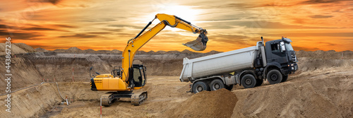 Fotografie excavator working on construction site with dramatic sky