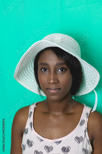 Young African American woman with vintage pink dress, hat and green background, in the city of Cali Valle del Cauca Colombia.