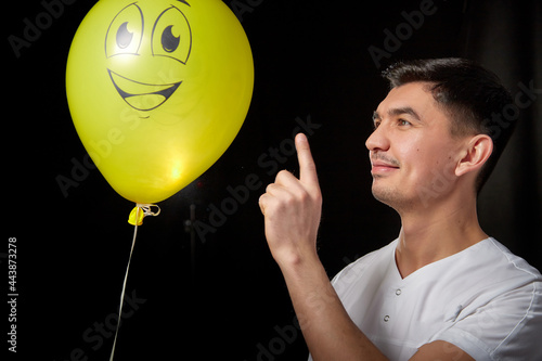 Portrait of a young man in a business suit and wigh with balloons. Positive guy posing in the studio photo