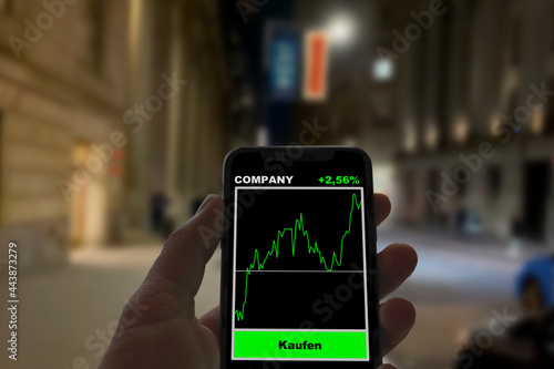 Person hält Smartphone mit einer Neo-Broker App im Hintergrund die Wall Street mit der NYSE, Aktienhandel, Börse, Digitalisierung, Finanzen, Geldanlage, Investieren