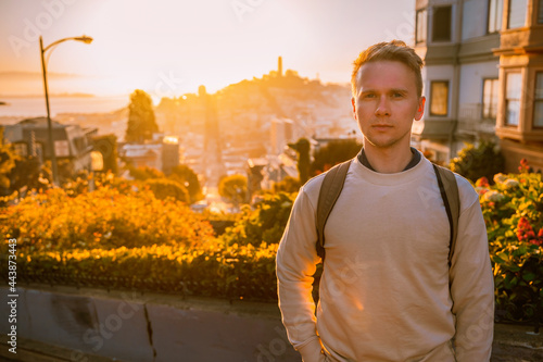 A young man stands on a beautiful Lombard Street during sunset in San Francisco