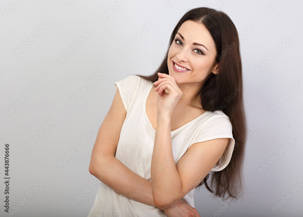 Thinking casual girl looking up with finger at face with smile on blue background. Closeup Thinking casual girl looking up with finger at face with smile on blue background. Closeup