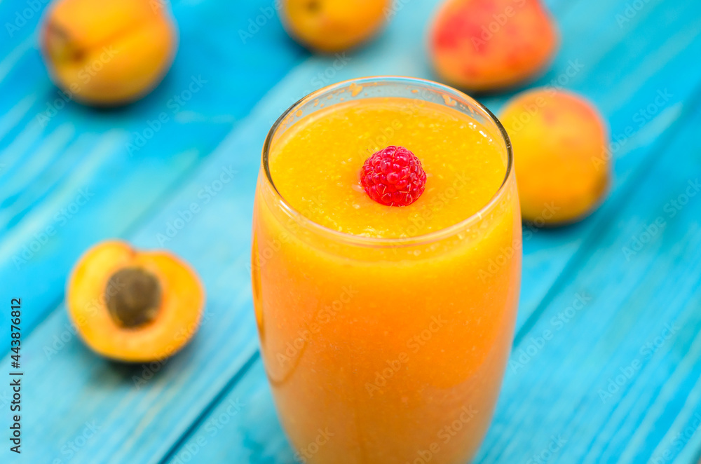 Glass of apricot and carrot juice on colourful turquoise blue painted wooden boards Glass of apricot and carrot juice on colourful turquoise blue painted wooden boards