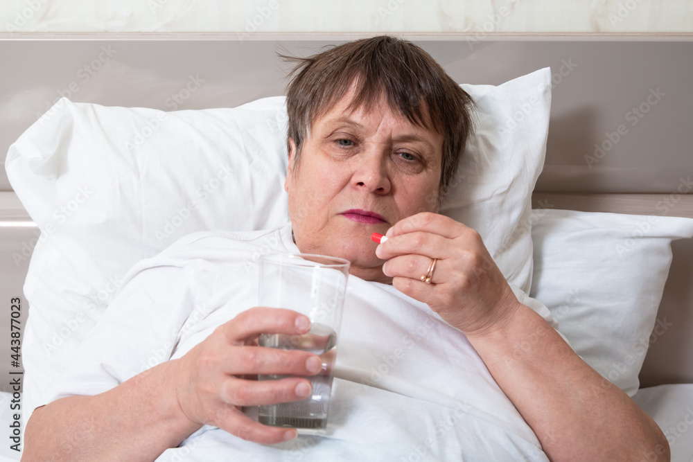 Sick elderly woman on the bed. Grandma is about to take her pills. Sick elderly woman on the bed. Grandma is about to take her pills.