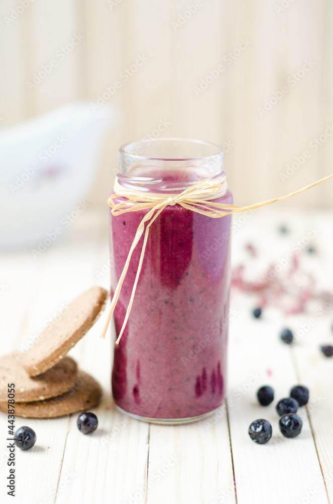 Cranberry and black currant smoothie in glass jars with cookies on a white wooden background Cranberry and black currant smoothie in glass jars with cookies on a white wooden background