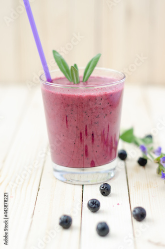 Cranberry and black currant smoothie in glass with cookies and mint on a white wooden background