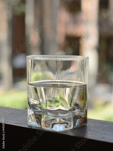 Glass shot with a transparent, colorless drink on a beautiful wooden tabletop on a blurry, unfocused background