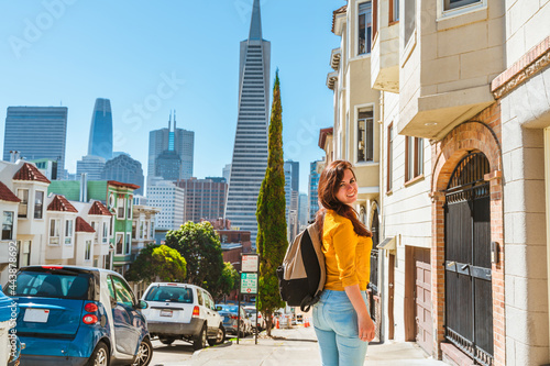 Cute young woman walks along a beautiful street with a view of the Transamerica Tower in San Francisco © KseniaJoyg