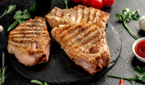 grilled pork steaks with spices on a stone background