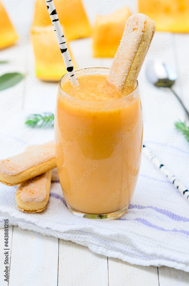 Glass of fresh cantaloupe smoothie with cookies and birch staraw on white wooden boards. Glass of fresh cantaloupe smoothie with cookies and birch staraw on white wooden boards.