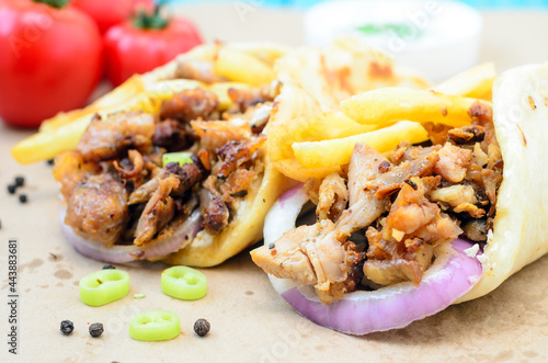 Traditiona Greek pita gyros with meat, fried potatoes, tomato, onion and drink on brown Paper, Placed on blue Wooden Table