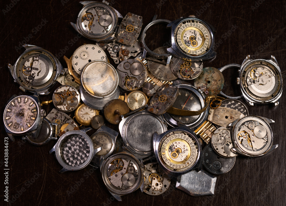 Old broken wristwatches disorderly lie on a dark background