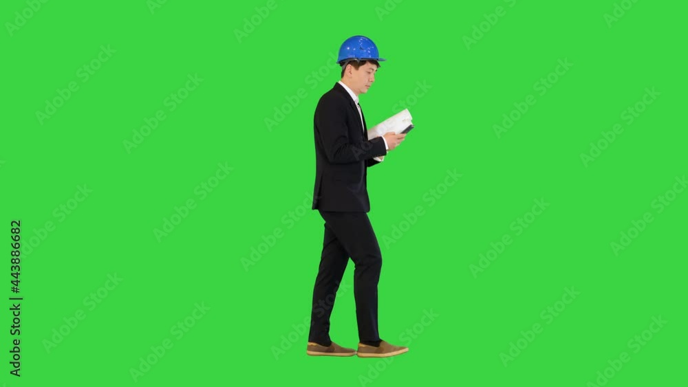 Architect man holding blueprints using smartphone and walking on a Green Screen, Chroma Key. Architect man holding blueprints using smartphone and walking on a Green Screen, Chroma Key.
