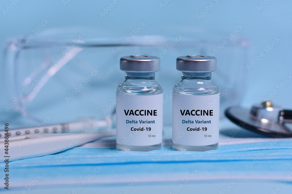Two Bottle of Covid-19 vaccine to immunize from the Delta Variant Coronavirus, syringe , face mask,body thermometer and protective glasses on blue background.The concept of medicine, healthcare Two Bottle of Covid-19 vaccine to immunize from the Delta Variant Coronavirus, syringe , face mask,body thermometer and protective glasses on blue background.The concept of medicine, healthcare