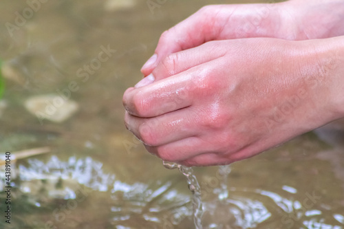 Young boy playing with clear water at a little creek using his hands and the water spring cooling his hands and refreshing with the pure elixir of life for zen meditation or environmental protection
