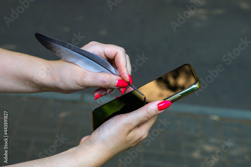 Obraz na plátně Woman tries to use a bird pen for smartphone.