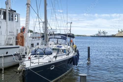 Sail yacht standing moored in the sea port, sailboat harbor Helsinki, Finland. Modern water transport, lifestyle. Three modern icebreakers in the background. Yachting, marine background.