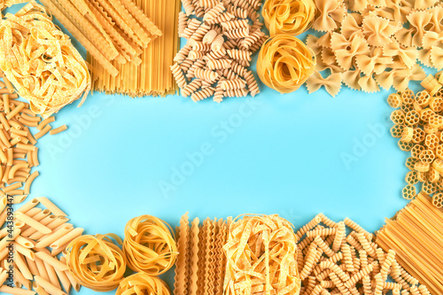 Frame from Assorted varieties of pasta wallpaper. Mix macaroni, spaghetti on blue background with copy space