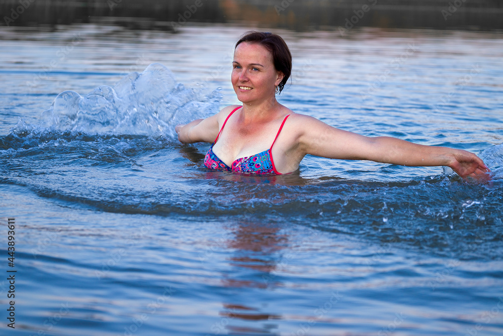 woman in swimsuit splashing hands standing in water