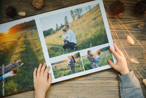 the Hand child holding a family photo album against the background of the a wooden table photo