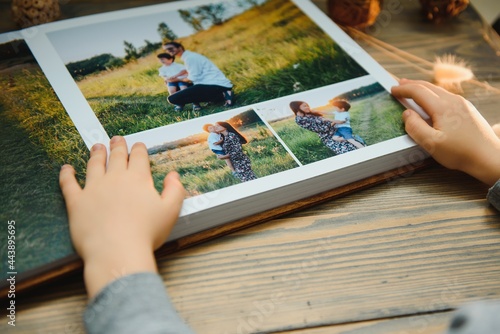 the Hand child holding a family photo album against the background of the a wooden table photo