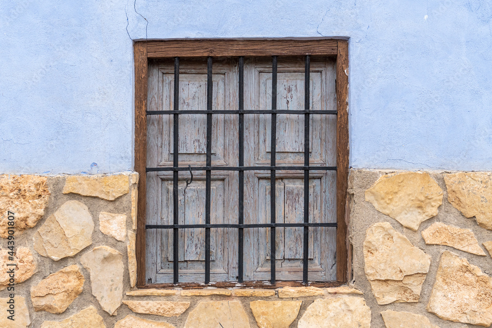 Rustic window with forged grating in a stone facade.
