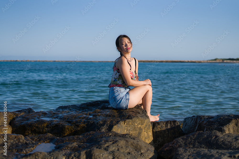 holidays lifestyle portrait of young Asian woman by the  sea -  happy and beautiful Korean girl  enjoying beach vacation trip relaxed and cheerful at beach rock cliff