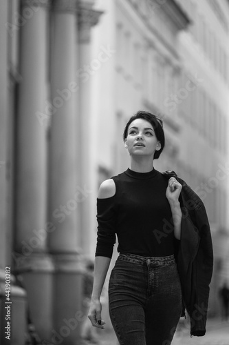 Black and white portrait of a happy young girl with short hair. Beautiful woman in classic black clothes walks around the city