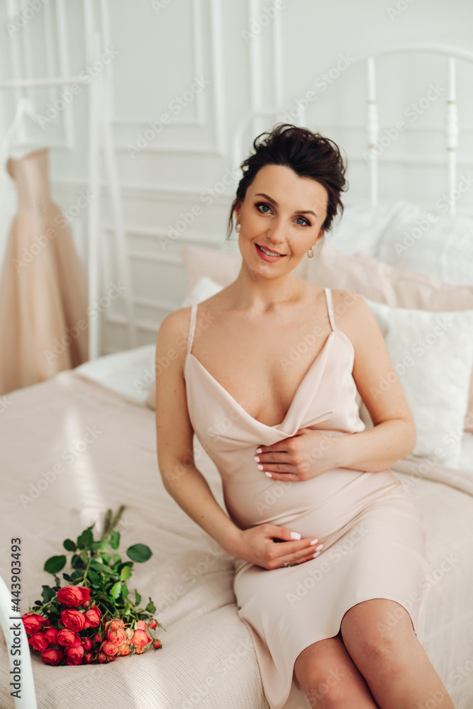 attractive pregnant woman in silk dress touches her belly with happy smile attractive pregnant woman in silk dress touches her belly with happy smile