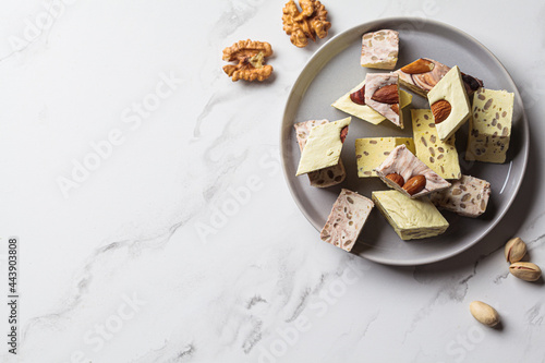 Pieces of halva on gray plate, white marble background, copy space. Middle eastern dessert concept. Healthly food.