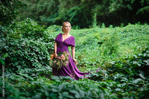 Girl model blonde in a lilac dress with a bouquet