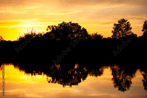 Sunset over the river  silhouette of the forest  mirror image in the water