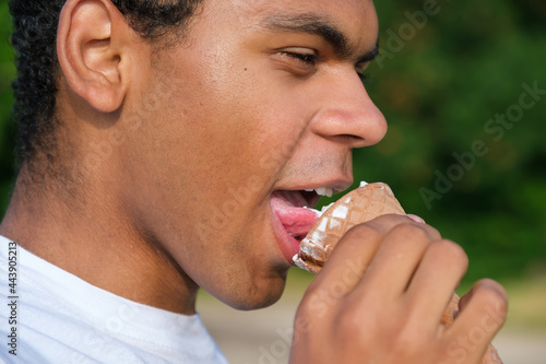 Portrait of a happy African American man enjoying ice cream outdoors in summer © Serhii