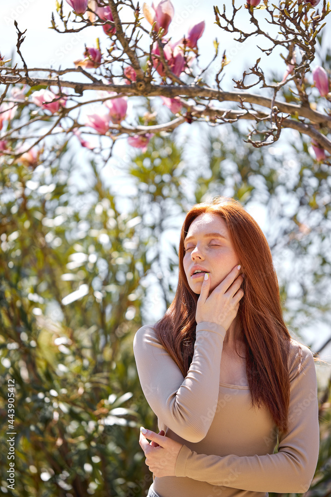 Relaxed woman posing in spring blossom flowers in blooming garden. Female beauty, fashion. Adorable lady inc asual shirt enjoying nature, inhale the scent of flowers, touching face. portrait Relaxed woman posing in spring blossom flowers in blooming garden. Female beauty, fashion. Adorable lady inc asual shirt enjoying nature, inhale the scent of flowers, touching face. portrait