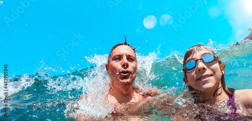 Wall Mural Father and daughter getting splashed by the waves