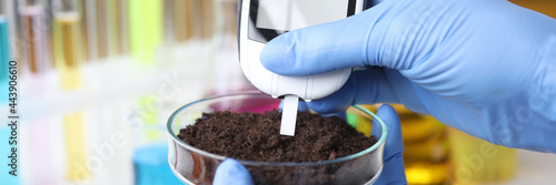 Scientist with gloves measures soil readings in test tube photo