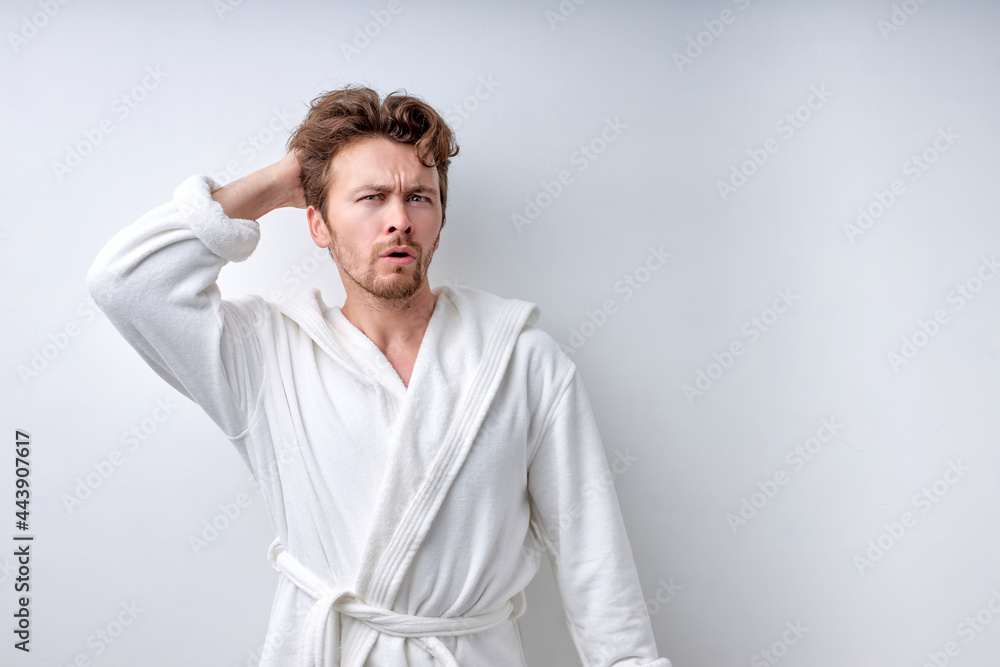 Doubting dissatisfied man at a loss, misunderstanding guy in bathrobe isolated on white studio background. Close-up Portrait of handsome caucasian guy in the morning, has question. Unsure and clueless Doubting dissatisfied man at a loss, misunderstanding guy in bathrobe isolated on white studio background. Close-up Portrait of handsome caucasian guy in the morning, has question. Unsure and clueless