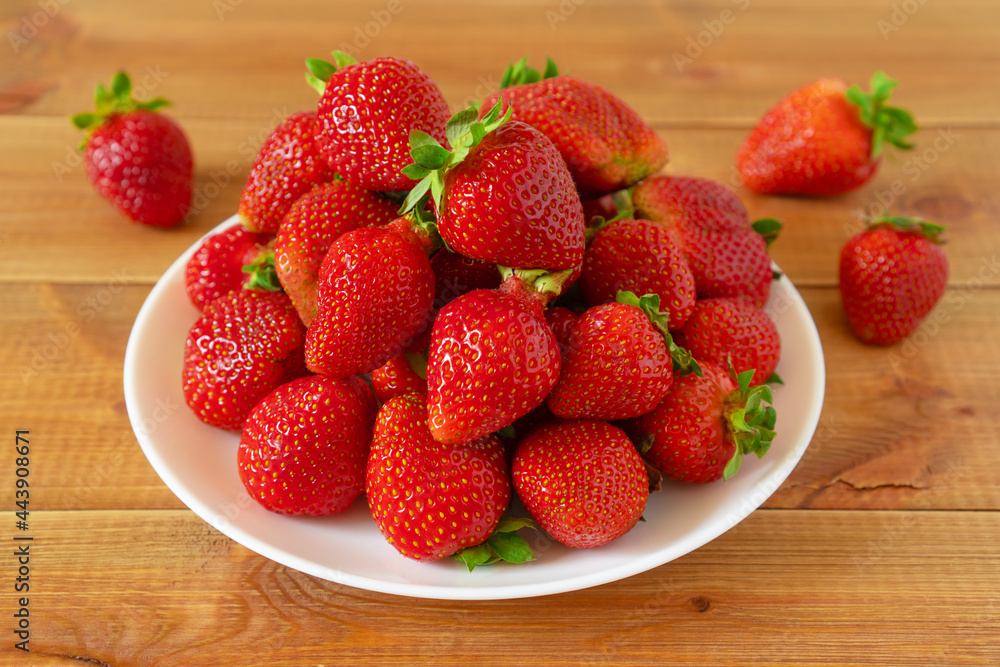 Plate of sweet red strawberries on wooden table. Delicious summer berries. Plate of sweet red strawberries on wooden table. Delicious summer berries.