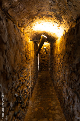 Small passage illuminated by electric torches inside the ruins of an old medieval castle in Olivenza, Spain