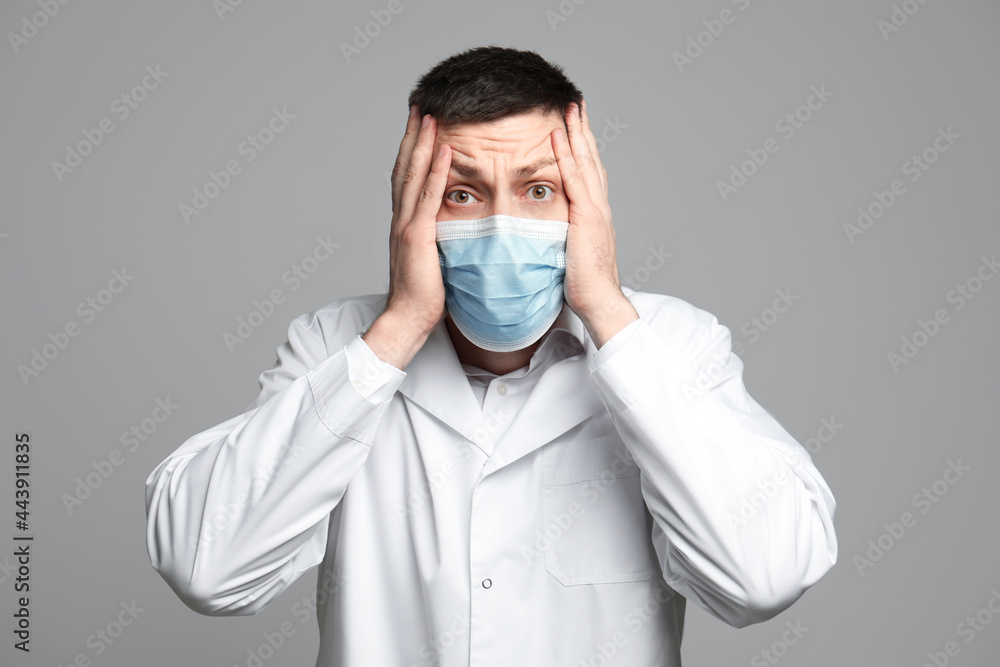 Portrait of doctor in protective mask feeling fear on grey background Portrait of doctor in protective mask feeling fear on grey background